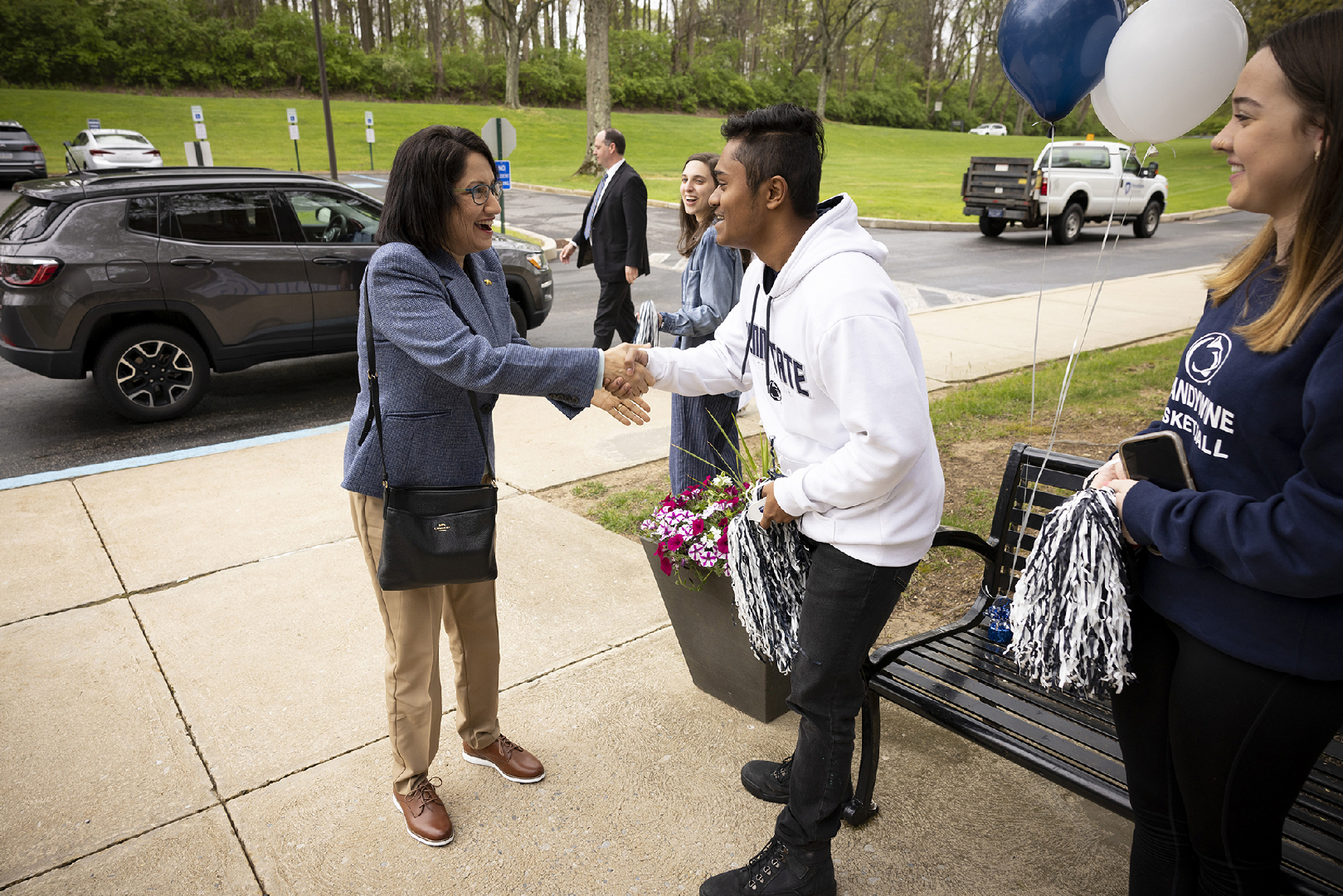 A woman shakes the hand of a male student.