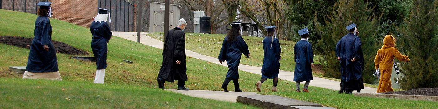 Students walking to commencement with Nittany Lion