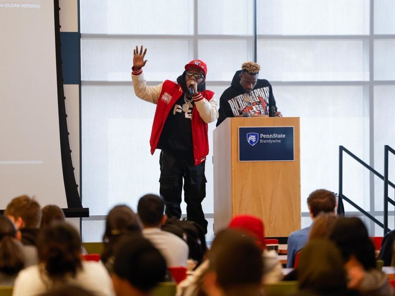 Philadelphia Freeway and DJ Crazy on stage with a large crowd of high schoolers