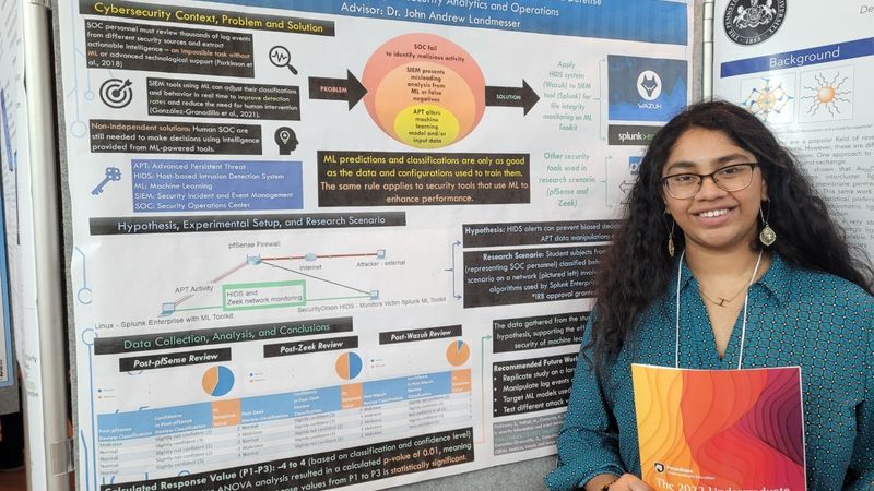 A female students stands in front of a research poster.