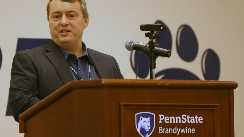 A man is speaking and standing behind a lectern.