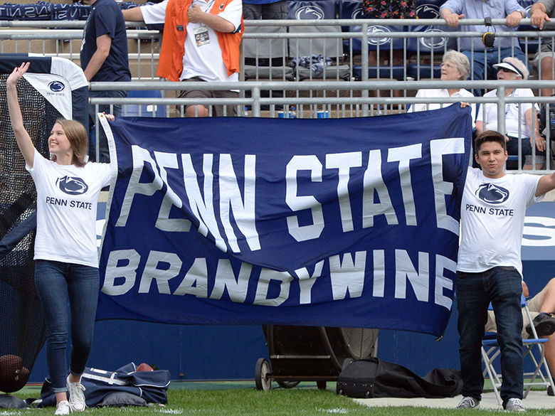 two students carrying a flag in the stadium for All-U Day