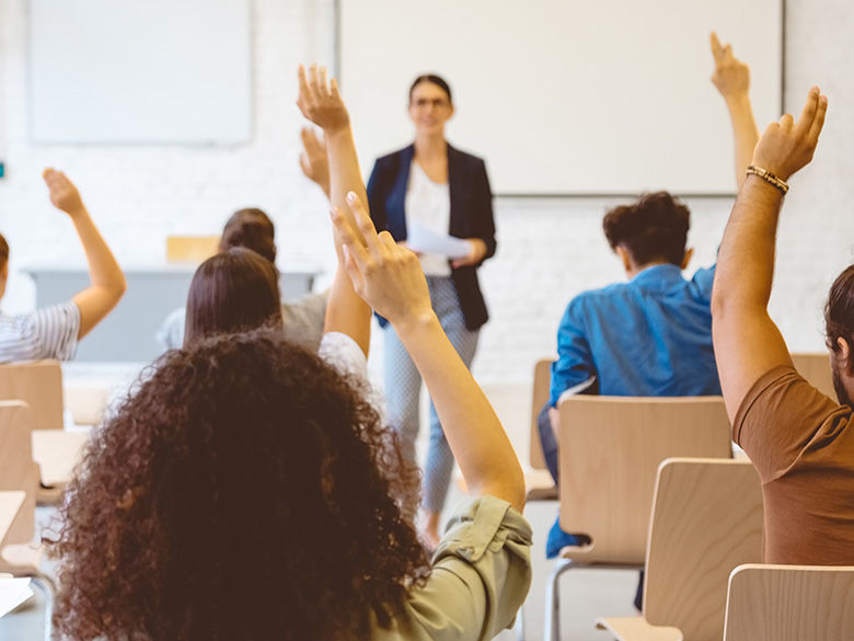 Students raising hands in classroom