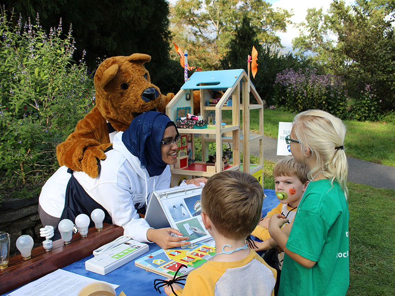 Student and lion mascot teaching children at community event.