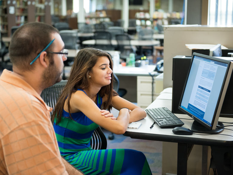 Female student working with male adviser on computer