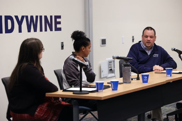 Three staff members sitting at a table with three microphones