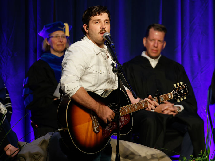 A student plays guitar and signs during Brandywine's commencement ceremony.