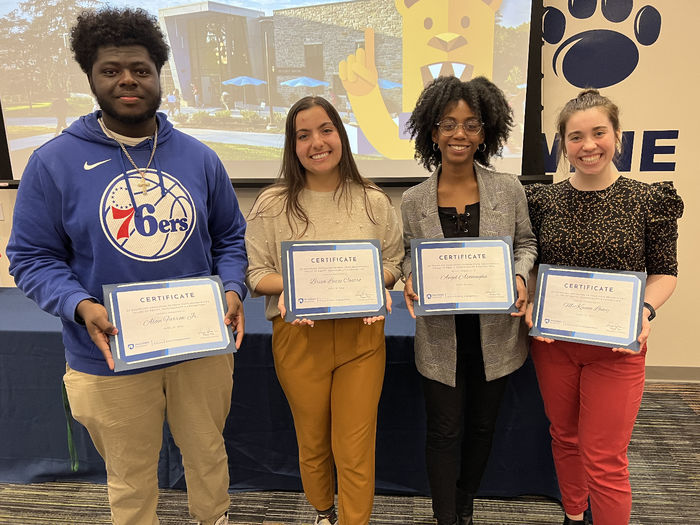 Four students hold certificates they received an an awards ceremony.