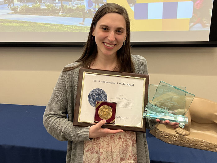 A female student holds an award certificate.