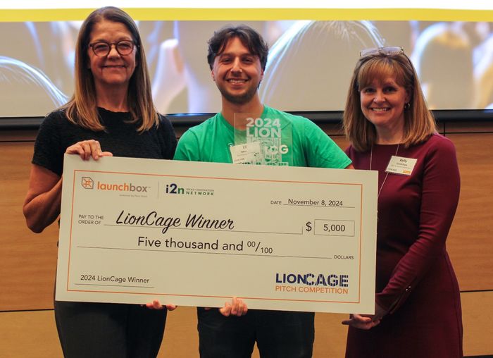 Eli Moraru, co-founder of the Community Grocer, poses with a giant check with prize money for his winning pitch.