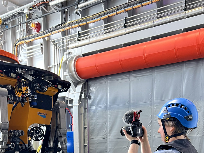 Gracie filming a video of a machine on the OceanX excursion