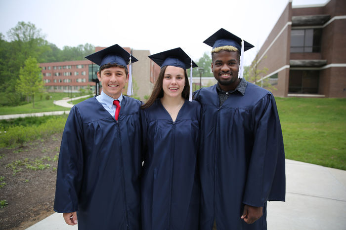 Three students smiling after Commencement ceremony.