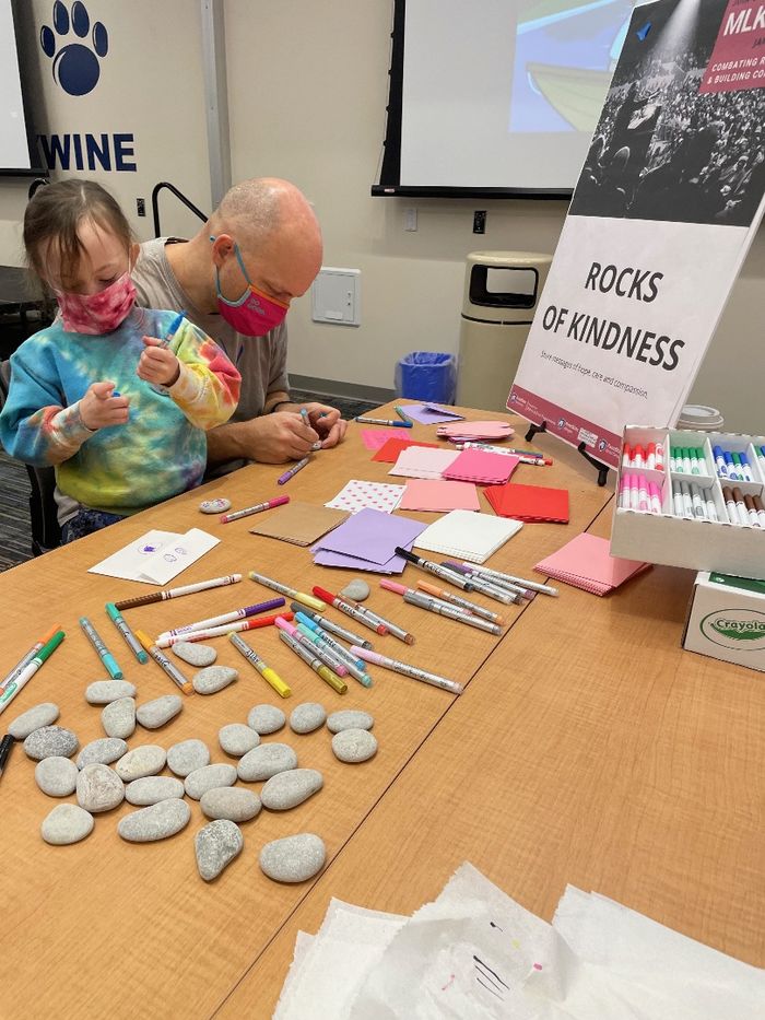 A father and daughter decorate rocks of kindness