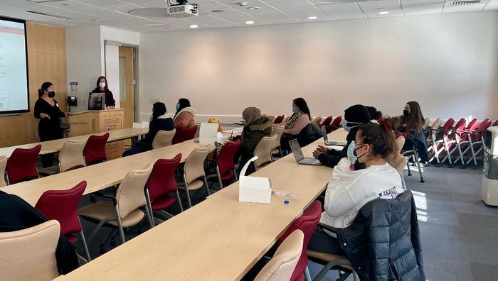 Students sit at desks in red chairs engaging with a speaker during a workshop on identity and values. 