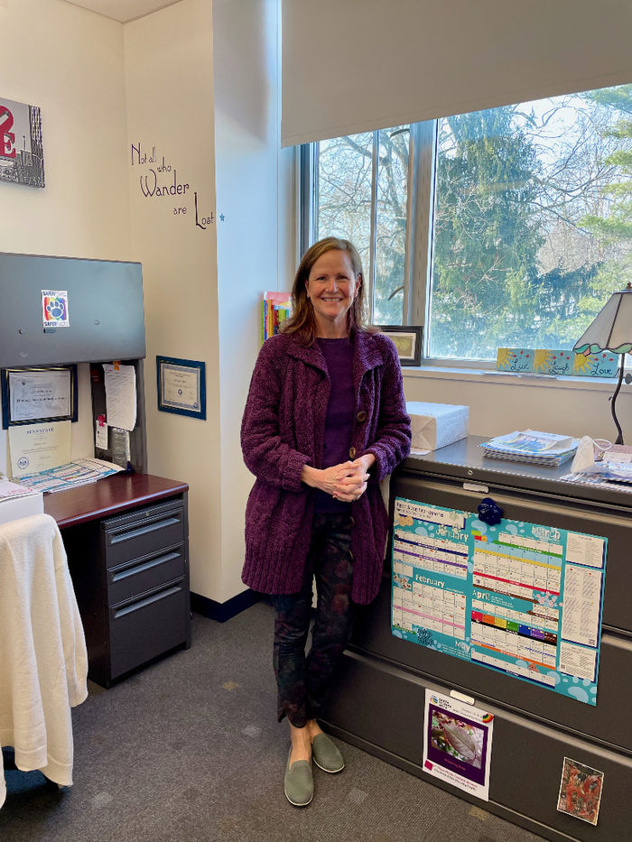 Christine Allen, Coordinator of Career Services stands in her office in front of a sign that reads "not all who wander are lost."