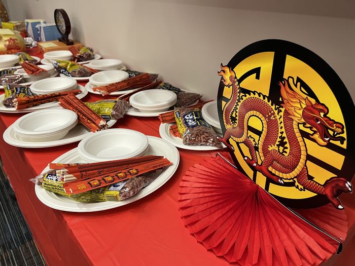 A table decorated for Lunar New Year including paper dragons, plates, chopsticks and a red tablecloth.