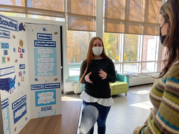 Student standing next to a poster.