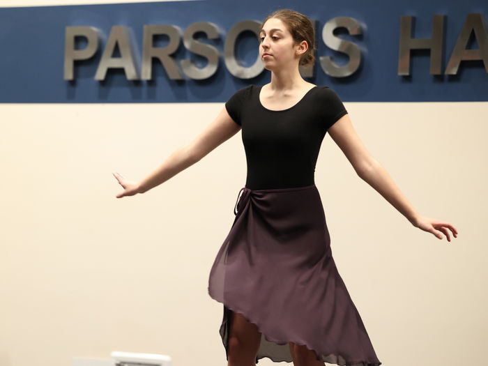 A female student is on a stage wearing a dance costume.