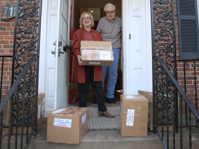 A man and a woman stand on a front porch with several boxes.