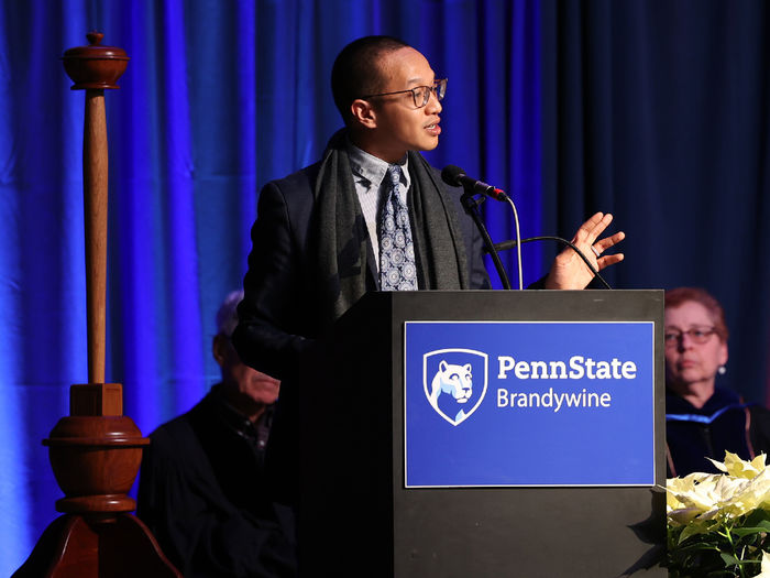 A man stands at a lectern speaking to an audience.