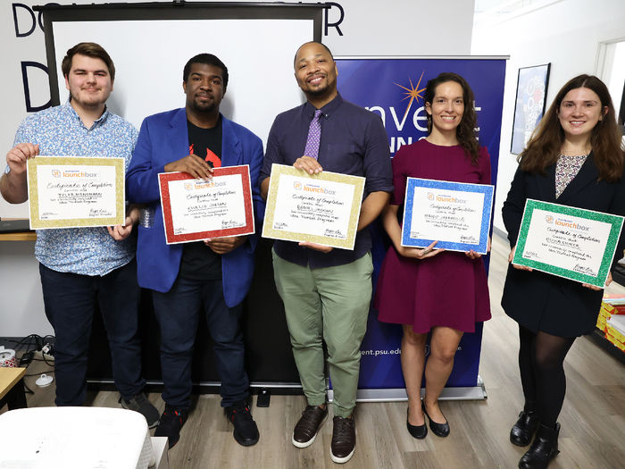 Five people stand holding their participation certificates.