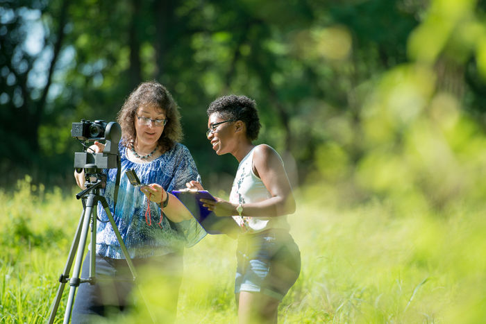 Professor and student conducting research outside.