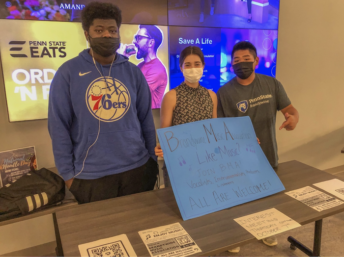 Three people wearing masks holding a sign to join BMA