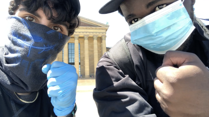 Filmmaker Jacob Mejias sits with friend Joshua Yeboah-Gyasi  in front of the Philadelphia Art Museum. 