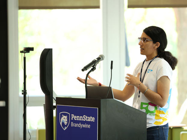 woman wearing glasses standing at a podium with microphone