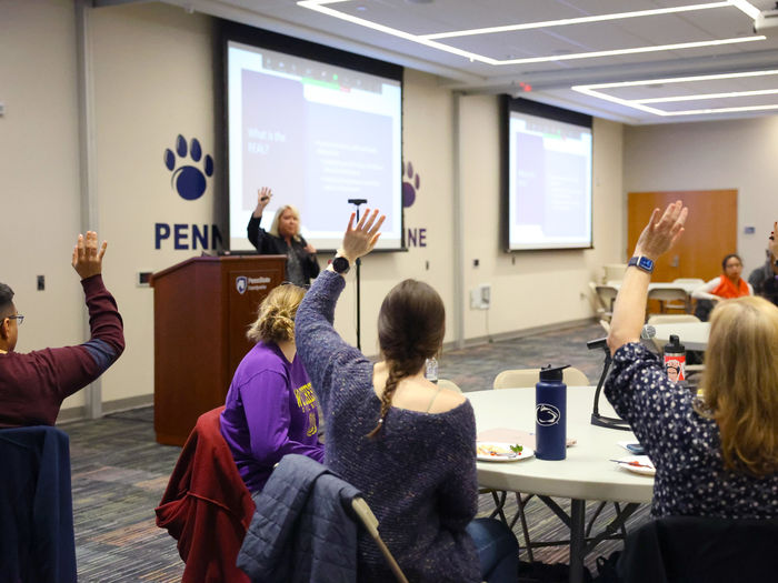 Members of the REAL raising their hands at a Town Hall meeting to show who is involved