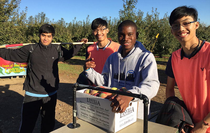 4 male students with box of apples