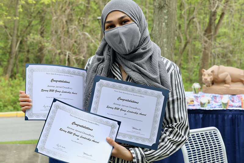 Female student sharing her three award certificates.