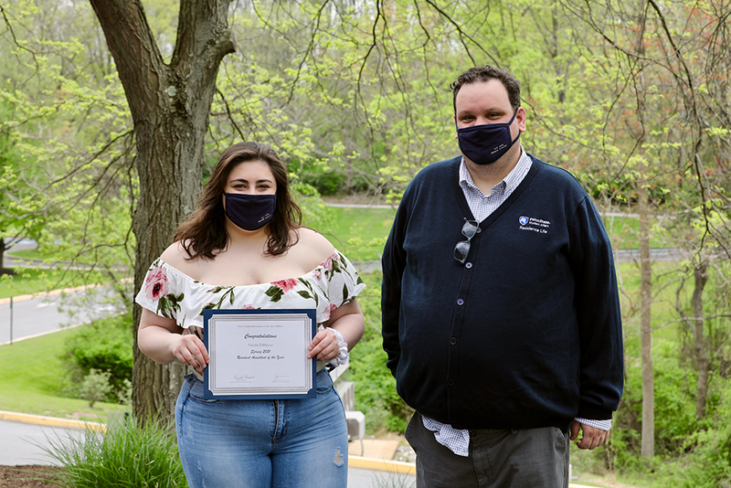 A student and her supervisor sharing her award certificate.