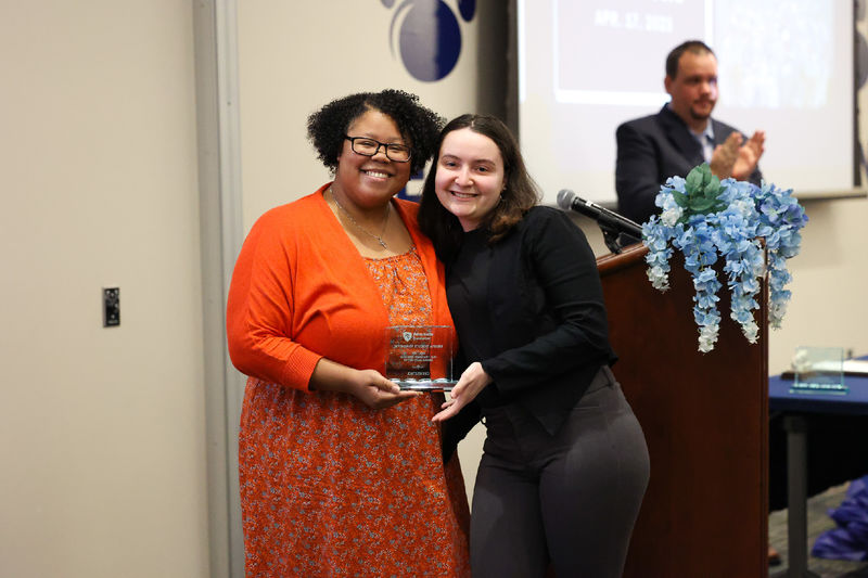 Two women posing holding an award