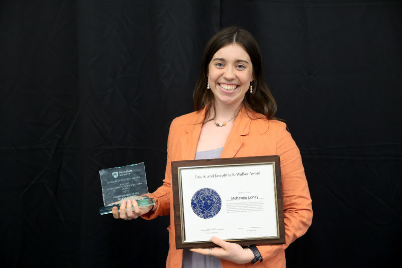 Woman smiling holding two awards