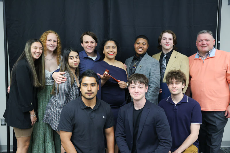 11 people smiling in front of a black backdrop