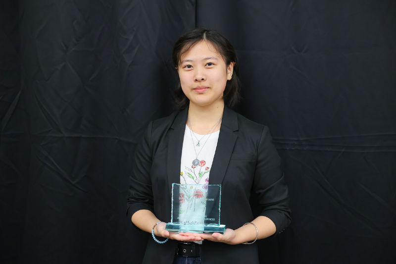 Woman holding an award in front of a black background