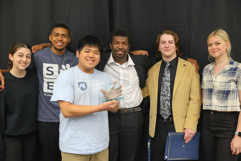 Six students smiling in front of a black backdrop