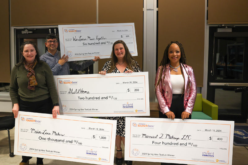 four people holding checks