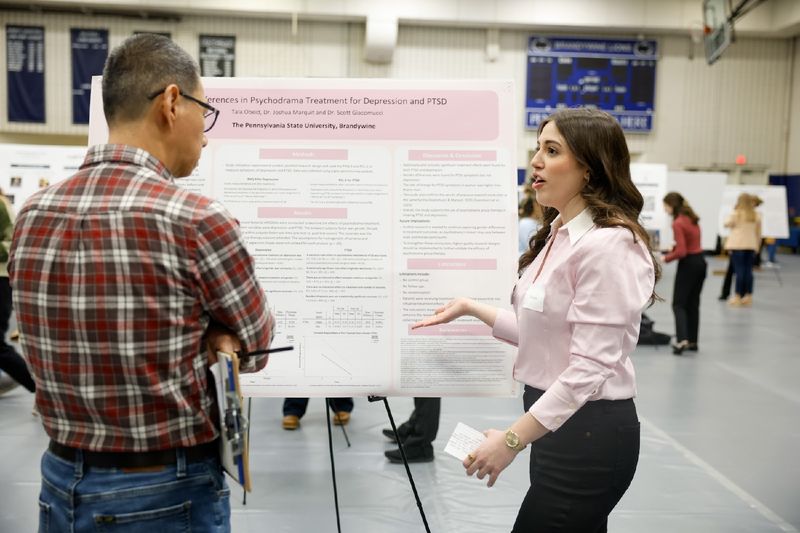 student presenting work on poster board