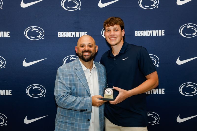 student holding baseball with coach