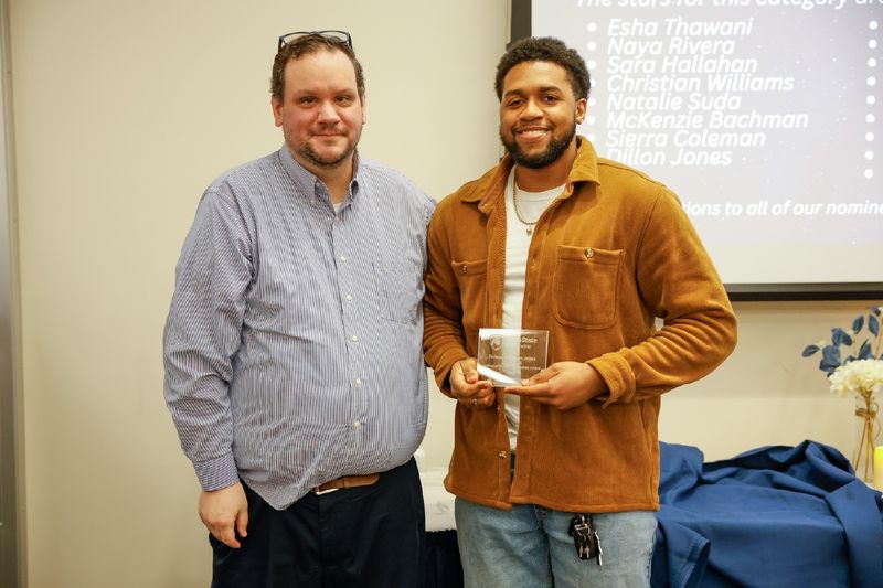 student with award and staff member