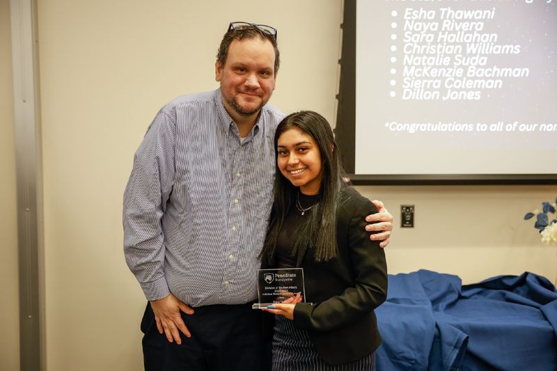 student and staff member with award