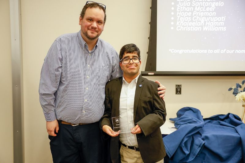 student and staff member with award