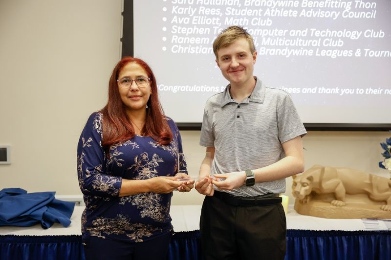 student and staff member with award