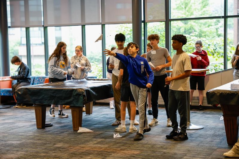 students flying paper airplanes