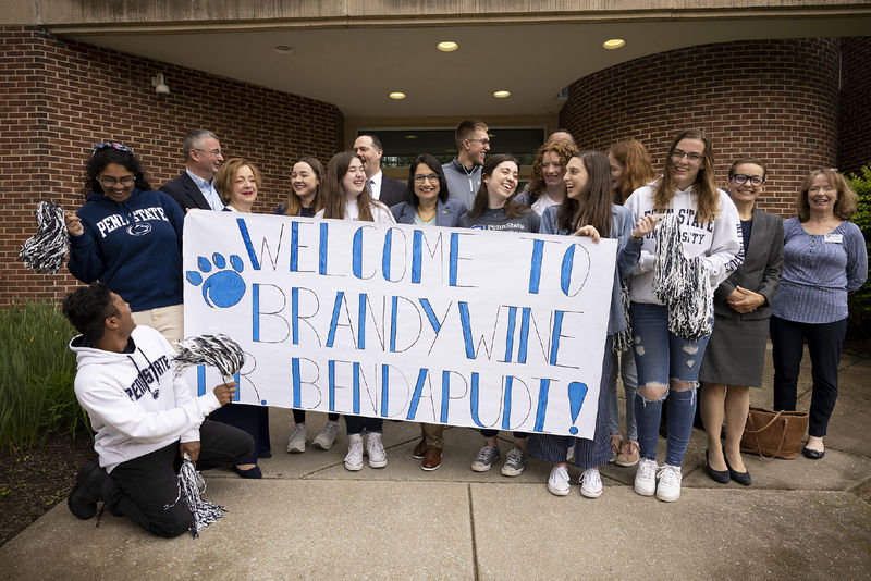 A group of 15 people stands behind a banner.