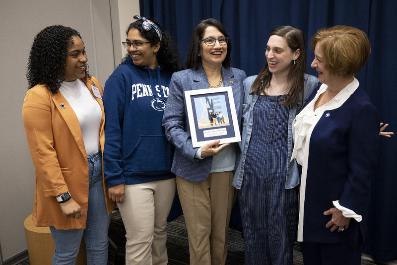 A group of five woman standing with one holding an artwork.