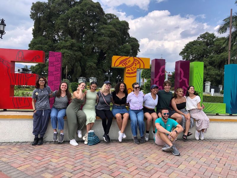 students sitting in front of sign that says "Santa Maria del Tule"