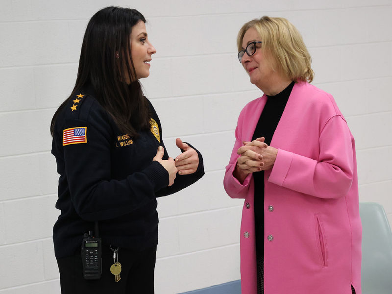 Two women stand talking to each other.